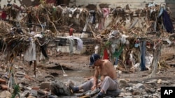 資料照片：洪災過後，一名男子在北京郊區的小溪裡洗衣服。他身後是一片狼藉。(2023年8月4日)