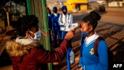 A pupil at the Winnie Mandela Secondary School has her temperature taken as she enters the school premises before classes resume in the Tembisa township, Ekurhuleni, South Africa, on June 8, 2020. 