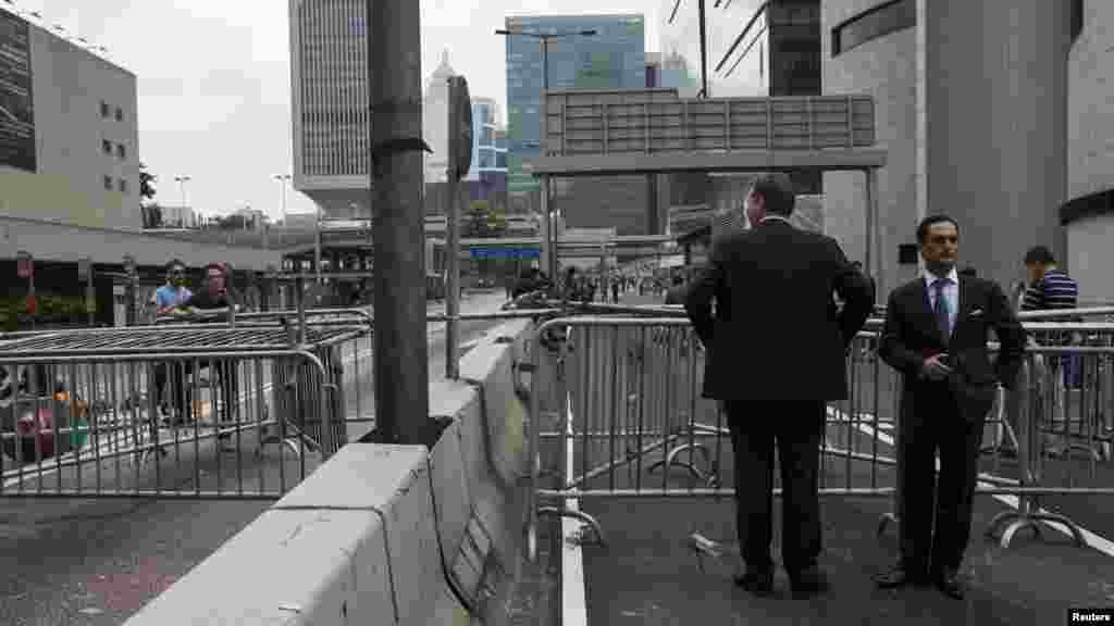 Businessmen stand in front of a road block set up by protesters at the main street of the financial Central district in Hong Kong, Sept. 29, 2014. 