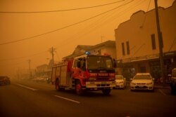 FILE - A fire truck moves up the main street of the New South Wales town of Bombala which is shrouded in smoke from nearby bushfires on Dec. 31, 2019.