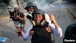 FILE - An injured member of the media is carried away during a rally against the government of Venezuelan President Nicolas Maduro and for the commemoration of May Day in Caracas, May 1, 2019.