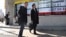 Men walk past an electronic stock indicator of a securities firm in Tokyo, Jan. 31, 2017.