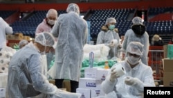 Volunteers help pack boxes of donated aid for elderly people who are banned from leaving their homes because of the coronavirus epidemic in Belgrade, Serbia, March 26, 2020.
