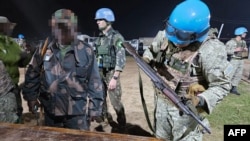 This handout picture released on Jan. 26, 2025, by the Uruguayan Army shows soldiers of the Armed Forces of the Democratic Republic of the Congo reportedly handing over their weapons to Uruguayan soldiers of the United Nations Organization Stabilization Mission in Goma.