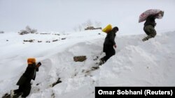 Warga Afghanistan yang selamat dari longsoran salju membawa makanan untuk orang lain di Desa Abdullah Khil di Distrik Dara, Provinsi Panjshir, 1 Maret 2015. (Foto: REUTERS/Omar Sobhani)