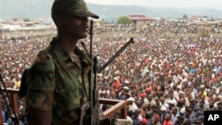 A soldier from the M23 rebel group looks on as thousands of Congolese people listen during an M23 rally, in Goma, eastern Congo, Nov. 21, 2012