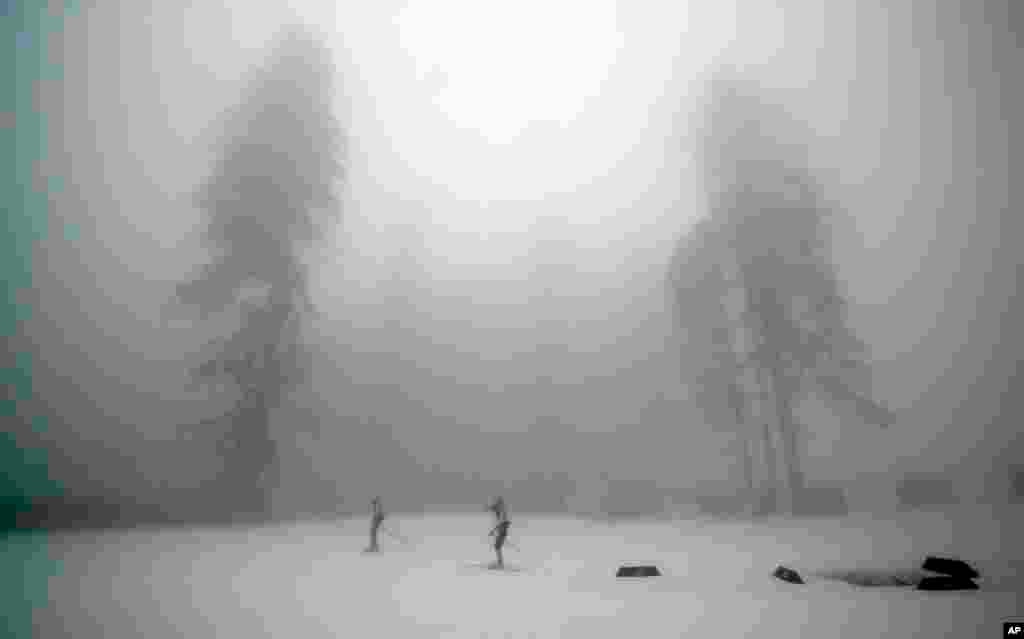 Athletes train as fog enshrouds the course of the men's biathlon 15k mass-start, at the 2014 Winter Olympics, Feb. 17, 2014.
