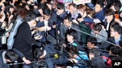 Choi Soon-sil, center left wearing black hat, a cult leader's daughter with a decades-long connection to President Park Geun-hye, is surrounded by prosecutor's officers and media at the Seoul Central District Prosecutors' Office in Seoul, South Korea, Oct. 31, 2016.