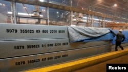 FILE - An employee removes a covering of aluminium ingots at the foundry shop of the Rusal Krasnoyarsk aluminium smelter in Krasnoyarsk, Russia, July 27, 2016. Russia is demanding compensation from the U.S. for its worldwide tariffs on foreign aluminum and steel Thursday, becoming the third influential member of the World Trade Organization to do so.