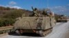 Tentara Israel mengacungkan tinju mereka dari kendaraan pengangkut personel lapis baja yang bergerak di Israel utara dekat perbatasan Israel-Lebanon, Selasa, 1 Oktober 2024. (Baz Ratner/AP)