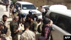 United Nations arms experts and opposition fighters are seen in Damascus' eastern Ghouta suburb on Aug. 29, 2013, as UN officials inspect the site where rockets had fallen during an investigation into a suspected chemical weapons strike near the capital.