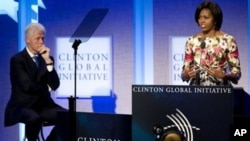 First Lady Michelle Obama (R) speaks while former President Bill Clinton (L) looks on during the closing plenary session of the annual Clinton Global Initiative (CGI) in New York City, 23 Sep 2010.