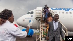 A health official uses a thermometer to measure the temperature of disembarking passengers at the airport at Mbandaka, Democratic Republic of the Congo, May 19, 2018.