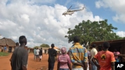 Residents look at a police helicopter patrolling near the closed house, where Italian volunteer for the Italian charity Africa Milele lived before she was seized, in Chakama trading centre of Magarini, Kilifi County, Kenya Nov. 21, 2018. 