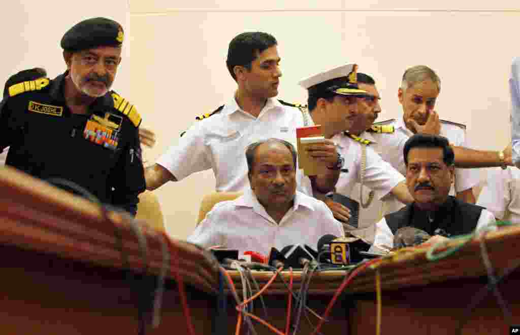 India’s navy chief, Admiral D.K. Joshi, left standing and Defense Minister A.K. Antony, center sitting, gesture during a press conference after an Indian navy submarine caught fire and sank in Mumbai, August 14, 2013.