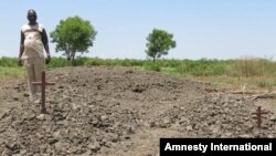 Rev Thomas Agou by the mass grave of 18 women killed by opposition forces in and around St Andrew's Cathedral in Bor in January 2014. © Amnesty International