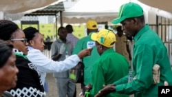 FILE - Party members have their temperature checked and sanitize their hands as a precaution against the coronavirus at the national congress of the ruling Chama cha Mapinduzi (CCM) party in Dodoma, Tanzania, July 11, 2020.