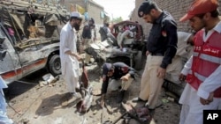 Pakistani police officers examine the site of a bomb blast in a bus stand in Matani near Peshawar, Pakistan, June 5, 2011