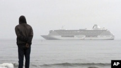 A man stands on the shores of the Bering Sea to watch the luxury cruise ship Crystal Serenity, anchored just outside Nome, Alaska, because it was too big to dock at the Port of Nome, Aug. 21, 2016.