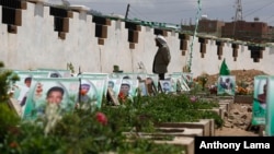 A Shi'ite rebel Houthi stands among the portrait adorned graves of Houthi fighters and supporters who were killed in the ongoing conflict in Yemen, a few hours before the start of a fresh cease-fire, in Sana'a, Yemen, April 10, 2016. 