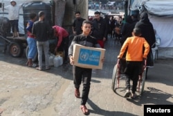 FILE - A Palestinian carries an aid box distributed by the U.N. Relief and Works Agency (UNRWA), amid the Israel-Hamas conflict, in Deir al-Balah, central Gaza Strip, Nov. 4, 2024.