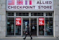 A woman wearing a face mask walks past a closed souvenir shop near Berlin's famed tourist magnet Checkpoint Charlie, Jan. 29, 2021, during the coronavirus pandemic.