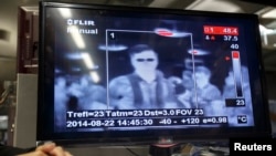 FILE - Passengers are screened with a thermal-imaging camera as they arrive at Bangkok's Suvarnabhumi Airport in Bangkok, Thailand, Aug. 22, 2014.