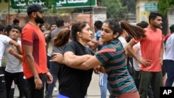 Indian wrestlers Vinesh Phogat, left, and Sangita Phogat practice wrestle as they participate in a protest against Wrestling Federation of India President Brij Bhushan Sharan Singh and other officials in New Delhi, India, April 28, 2023. 