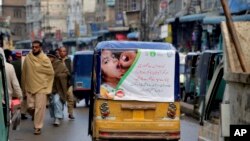 Sebuah becak mobil dengan poster yang mengiklankan kampanye polio melewati pasar di Peshawar, Pakistan. Pakistan. (Foto: AP)