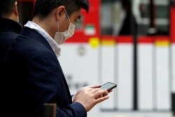 A man wears a protective mask as he looks at his mobile phone, following the outbreak of the new coronavirus, in Hong Kong, China, Feb. 10, 2020.