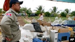 Seorang polisi Kamboja menjaga peralatan pembuat aneka narkoba yang disita dari pinggiran Phnom Penh. (Foto: Dok)
