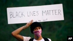 A protester holds up a sign in front of City Hall, May 30, in Phoenix, protesting the death of George Floyd.