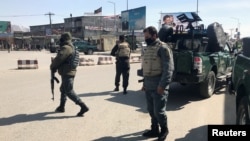 FILE - Policemen keep watch near the side of an attack in Kabul, Afghanistan, March 7, 2019.