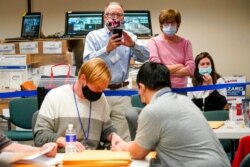 FILE - Republican canvas observer Ed White, center, and Democratic canvas observer Janne Kelhart watch as Lehigh County workers count ballots, in Allentown, Pennsylvania.
