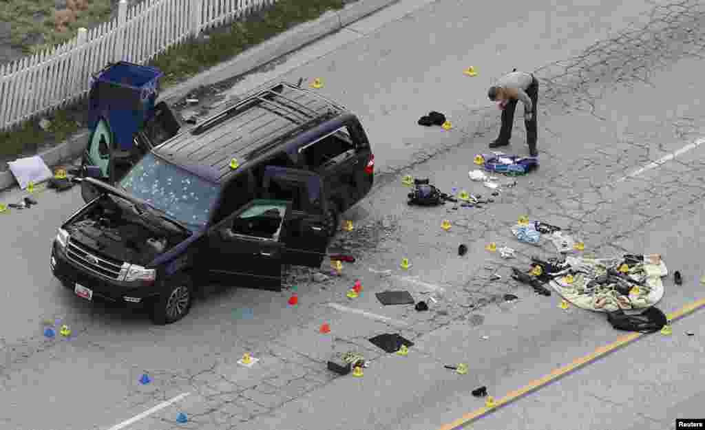 A law enforcement officer looks over the evidence near the remains of a SUV involved in the Wednesday&#39;s attack in San Bernardino, California, Dec. 3, 2015. Authorities were working to determine why a man and a woman opened fire at a holiday party of his co-workers in Southern California, killing 14 people and wounding 17 in an attack that appeared to have been planned.