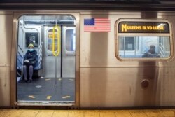 Commuters wear face masks for protection against the coronavirus as they ride the M train in New York, April 10, 2020.