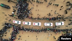 ภาพโดรนแสดงให้เห็นชาวปาเลสไตน์และนักรบรวมตัวกันรอบๆ รถของสภากาชาดในวันที่ฮามาสส่งมอบศพตัวประกันที่เสียชีวิต ซึ่งถูกจับกุมระหว่างการโจมตีโดยฮามาสเมื่อวันที่ 7 ตุลาคม 2023 ที่คานยูนิส ตอนใต้ของฉนวนกาซา 20 ก.พ. 2025 (REUTERS/Stringer)