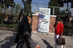 Iranians walk past anti-U.S. graffiti on the wall of the former U.S. Embassy, in Tehran, Iran, Oct. 15, 2019.