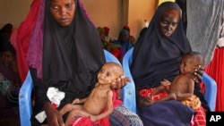 FILE - Malnourished babies are held by their mothers, both of whom fled the drought in southern Somalia, at a feeding center in a camp in Mogadishu, Somalia, Feb. 25, 2017.