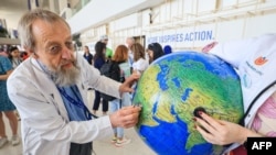 Environmental activists stage a protest with a earth globe during a demonstration at the venue of the COP28 United Nations climate summit in Dubai on Dec. 6, 2023.
