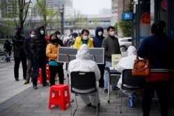 People wearing face masks line up outside a Hankou Bank branch in Wuhan, Hubei province, China, March 31, 2020.
