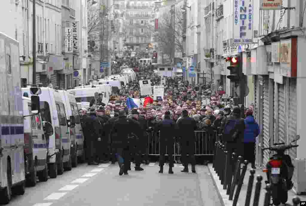 Police block a street to hold back the public demonstration near Place de la Republique in Paris, Jan. 11, 2015.