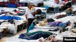 FILE - A migrant kisses a child as they rest at an improvised temporary shelter in a sports hall in Hanau, Germany, Sept. 24, 2015. 