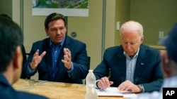 President Joe Biden listens as Florida Governor Ron DeSantis speaks during a briefing in Miami Beach, Florida, July 1, 2021, about the collapsed condo tower in Surfside.
