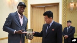 Former NBA basketball star Dennis Rodman presents a book titled "Trump The Art of the Deal" to North Korea's Sports Minister Kim Il Guk Thursday, June 15, 2017, in Pyongyang, North Korea. (AP Photo/Kim Kwang Hyon)