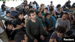 FILE - Suspected Uighurs from China's troubled far-western region of Xinjiang, sit inside a temporary shelter after they were detained at the immigration regional headquarters near the Thailand-Malaysia border in Hat Yai, Songkla, March 14, 2014.