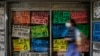Una mujer camina frente a carteles que muestran los precios de los productos en dólares, frente a una tienda en Caracas, el 18 de enero de 2022. Foto: AP.