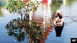 A man rows his passenger on a boat past the shadow of the flooded Chatkaew Chongkolnee temple in Bangkok, Thailand, November 1, 2011.