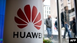 A pedestrian walks past a Huawei product stand at an EE telecommunications shop in London, April 29, 2019