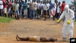 A health worker, right, sprays a man with disinfectant chemicals in Monrovia, Liberia, Sept. 4, 2014.